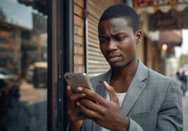 Nigerian small business owner checking their Google Business Profile listing on a smartphone outside their storefront.