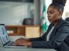Abuja business owner reviewing her company website's enquiry page on a laptop in a corporate office.